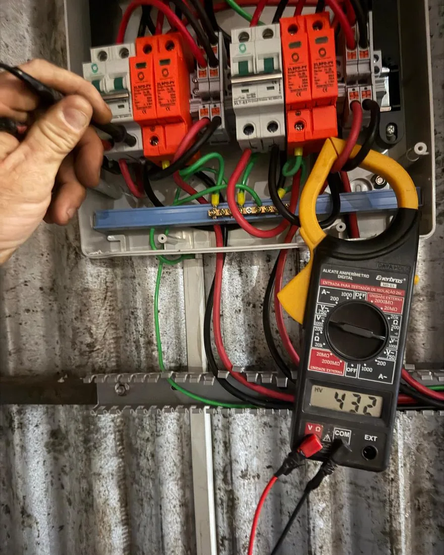 Técnico da Solares Premium medindo tensão no string box com alicate amperímetro